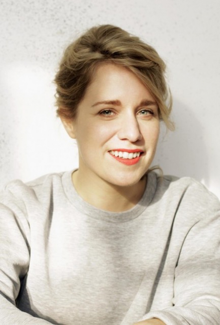 A portrait of a woman wearing a grey jumper with a white background